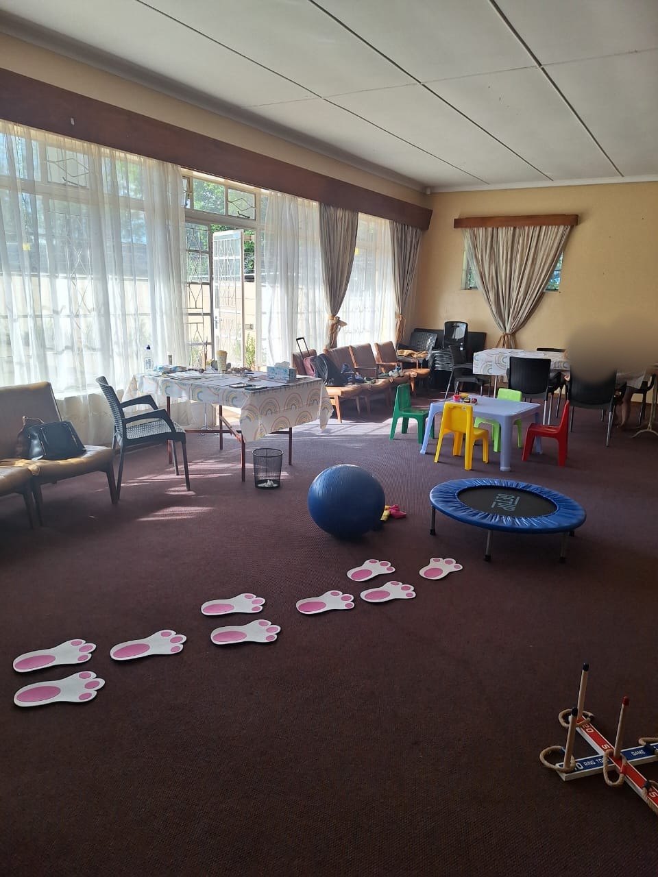 The play space with bunny footprints, a trampoline and colourful chairs; children's faces blurred