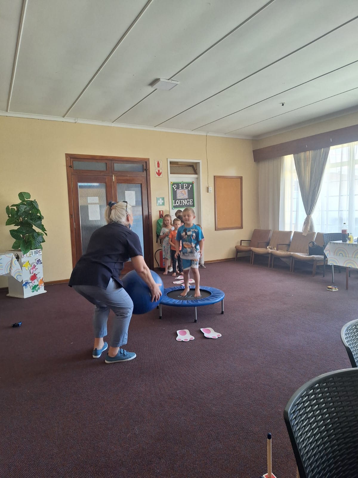 Karen playing a ball game with young children in the play room